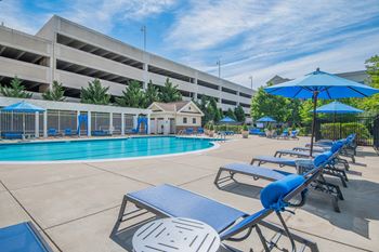 a swimming pool with lounge chairs and umbrellas next to a building